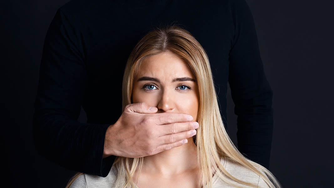 A white woman's face. A man's hand over her mouth.